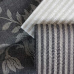 Close-up of Damasco Rustica floral and Iris Rustica striped linen towels in black, grey and natural tones.
