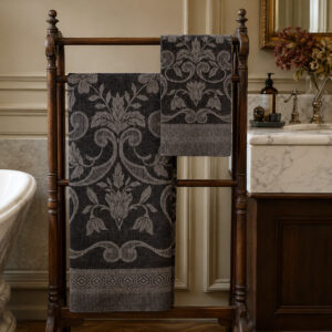 Black Damasco Rustica linen towels with a woven floral motif, displayed on a wooden towel rack in a classic bathroom.