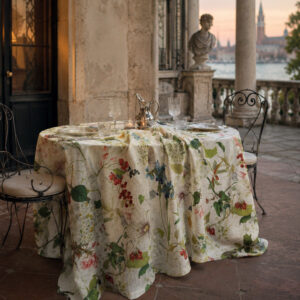 Ibisco tablecloth on a round table on a Venetian terrace at sunset, with wrought iron chairs, stone bust and the lagoon in the background