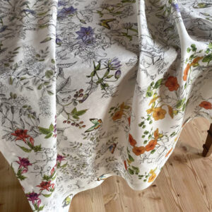 Close-up of the Gravure pure linen tablecloth draped over a table, with flowers, leaves and butterflies