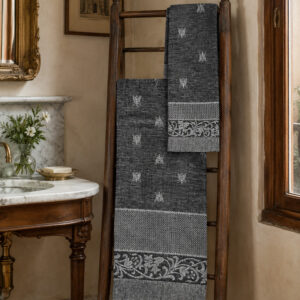 Asciugamani Ape in lino nero con motivo ad api, appesi a una scala di legno in un elegante bagno italiano.