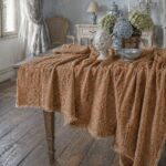 Optical linen tablecloth in rust color, draped over antique table with hydrangea centerpiece and blue and white ceramics