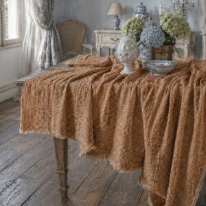Optical linen tablecloth in rust color, draped over antique table with hydrangea centerpiece and blue and white ceramics