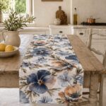 Pansé linen table runner on a light wood table in a farmhouse kitchen, with lemons and a jug of olive branches