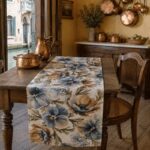 Pansé linen table runner on a rustic wooden table by a Venetian window overlooking a canal, with copper pots and a copper pitcher