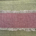 Close-up of Diana in moss green linen with an antique rose band and fringe along the band's edges.