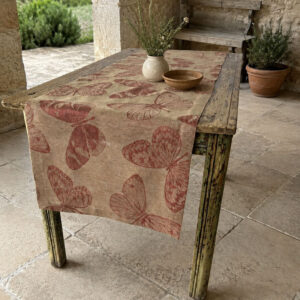 Fauna Sagrantino linen table runner on an antique table under an Italian country house loggia