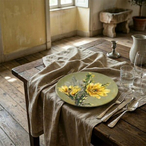A rigid charger plate adorned with a cactus flower motif, styled on a table covered with a natural linen tablecloth.