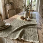 Green Intersezioni jacquard hemp and cotton table runner on a rustic wood table.