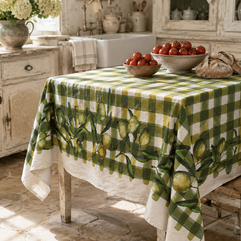 Olive Print Linen Tablecloth – Murge-La-Bottega-di-Casa Murge olive print linen tablecloth on a kitchen table styled with fresh tomatoes and rustic bread.