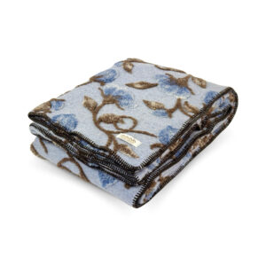Folded Narciso Blue boiled wool throw with raised blue flowers and brown stems on powder blue, finished with dark edge stitching.